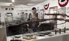 A person is observing a glass display case containing firearms and ammunition in a museum exhibit.