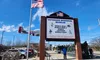 The image shows the entrance to a Veterans Memorial Museum with a marquee listing various wars, an American flag, and a vintage aircraft displayed nearby.
