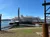 A large paddleboat-style ship is docked at a lakeside pier under a clear blue sky.
