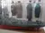 The image shows a display case featuring a detailed ship model with military uniforms exhibited in the background.