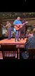 A group of musicians is performing on stage with guitars in front of an audience seated at tables.