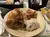 The image shows a plate of food with roasted chicken, pulled pork, and mashed potatoes, accompanied by a drink and some condiments in the background.