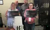 Four people are standing in a room holding signs with humorous text, suggesting they participated in a challenge or escape room.