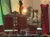 The image shows a vintage-themed interior with a red velvet loveseat, roses on a coffee table, and a red dress on a mannequin, creating an elegant atmosphere.