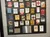 The image shows a framed display of various vintage cigarette packages with a plaque explaining they were collected by a Red Cross nurse during World War II.