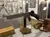 The image shows a museum exhibit displaying a World War II-era firearm, knife, and other military artifacts with informational displays and uniforms in the background.