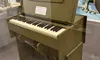 The image shows a vintage folding chaplain's field pump organ displayed in a museum exhibit, surrounded by military artifacts and historical memorabilia.