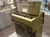 The image shows a vintage folding chaplain's field pump organ displayed in a museum exhibit, surrounded by military artifacts and historical memorabilia.