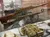 The image shows a museum display featuring a historical rifle, various military gear, and a sign labeled 
