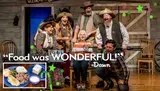 A group of people in Western wear are joyfully posing on a rustic set, embodying the festive spirit of a Christmas-themed event or production.