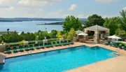 An outdoor swimming pool with loungers overlooks a scenic lake, offering a tranquil recreational space.