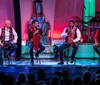 Four men are performing on stage during a Christmas show with colorful lights and festive decorations in the background