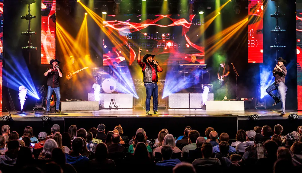 A lively country band performs on stage with vibrant lighting effects in front of an engaged audience