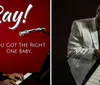 The image shows a smiling man wearing sunglasses and a tuxedo in front of a red background with the text Ray and a tagline You Got the Right One Baby along with a classic microphone which suggests its a promotional material likely for a music-related subject