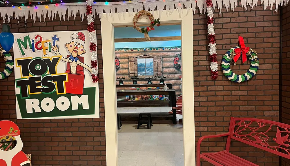 The image shows a festive doorway decorated with Christmas wreaths and garlands leading into a Matts Toy Test Room adorned with colorful signage and visible stuffed toys inside
