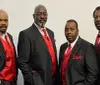 The image features four sharply-dressed men in suits with red accents posing for The Best of MOTOWN and More graphic backdrop with musical motifs