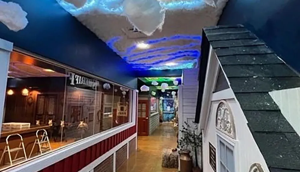 The image shows an indoor space creatively designed to resemble a quaint village street complete with storefront facades and a simulated night sky ceiling