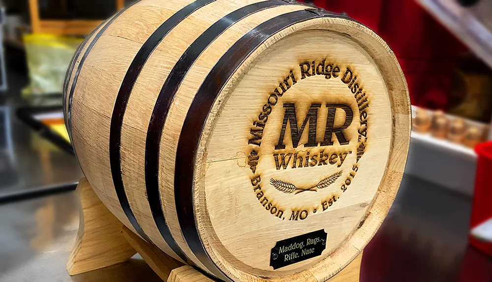 The image shows a close-up of a small wooden whiskey barrel with branded details indicating it is from the Missouri Ridge Distillery