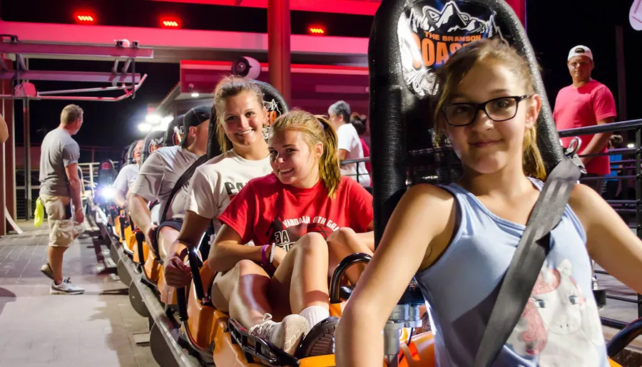 The image shows smiling people securely strapped into a ride called 'The Branson Coaster,' suggesting they are about to experience an amusement park attraction.