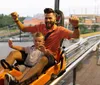 A child is enjoying a ride in an orange mountain coaster among the trees