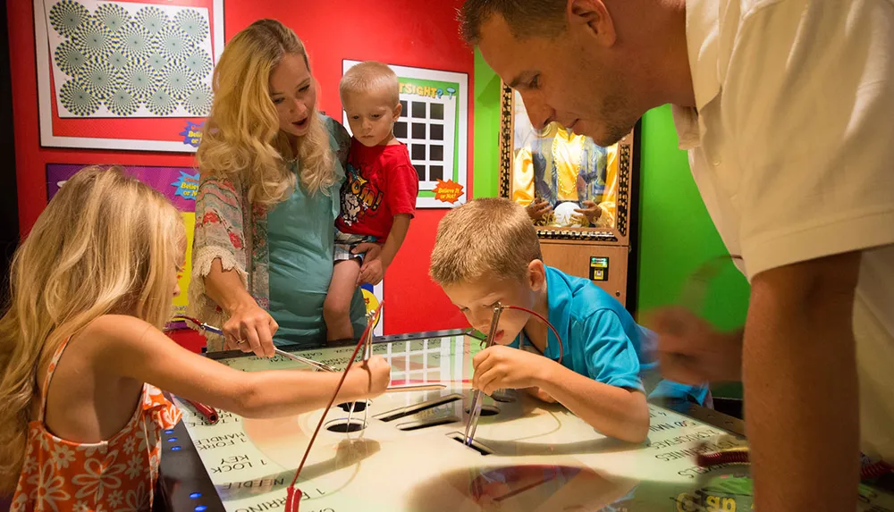 A family is engaged in an interactive exhibit with adults and children focused on an activity at a table