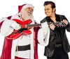 A person dressed as Santa Claus plays a red guitar while smiling at a performer styled like Elvis Presley who is also holding a guitar against a white background