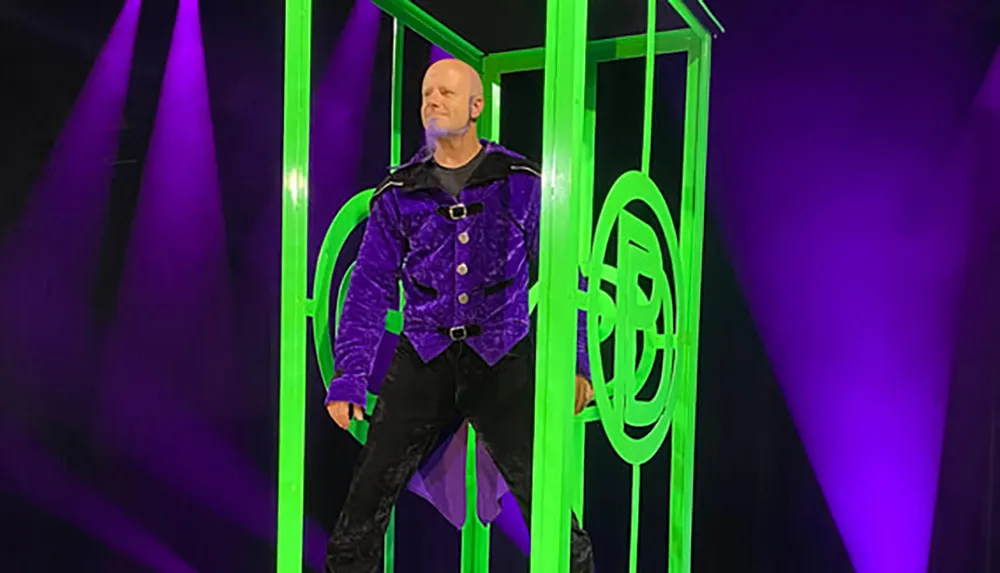A person is standing confidently in front of a bright green neon-lit structure with a purple-lit background