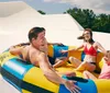Three people are enjoying a sunny day at a water park sliding down in a large inflatable ring with big smiles on their faces