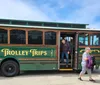 People are boarding a trolley-style tour bus on a sunny day