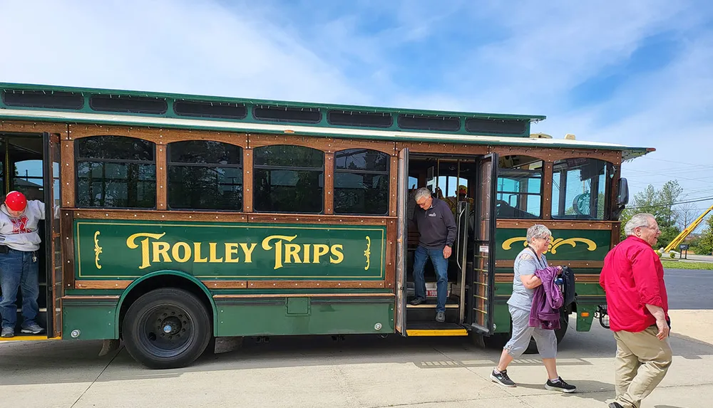 People are boarding a trolley-style tour bus on a sunny day