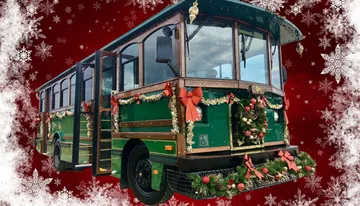 A vintage-style trolley is decorated with festive Christmas wreaths and bows, set against a seasonal background with snowflake decorations.