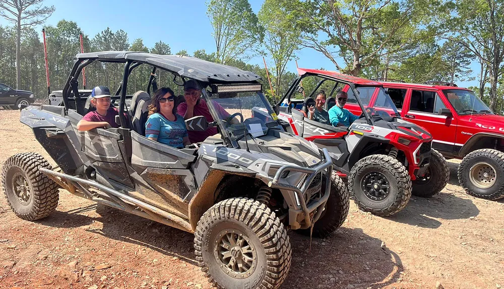 A group of people are enjoying an outdoor adventure sitting in off-road vehicles and posing for a photo on a sunny day