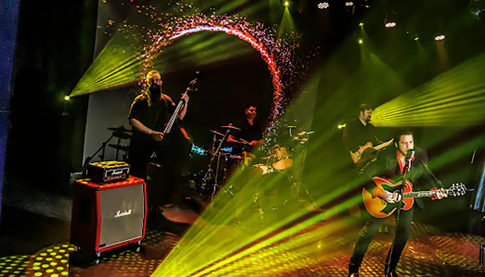 A band is performing on stage with vibrant lighting effects and a backdrop featuring a circular pattern
