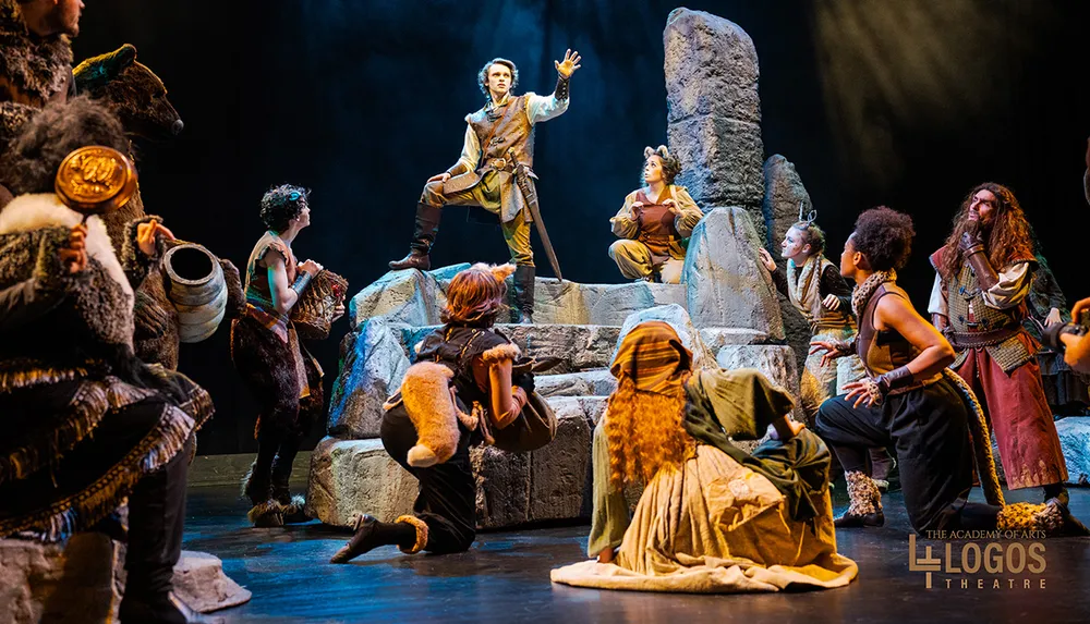 A theatrical performance features actors in elaborate costumes as they engage in a dramatic scene on a rocky stage