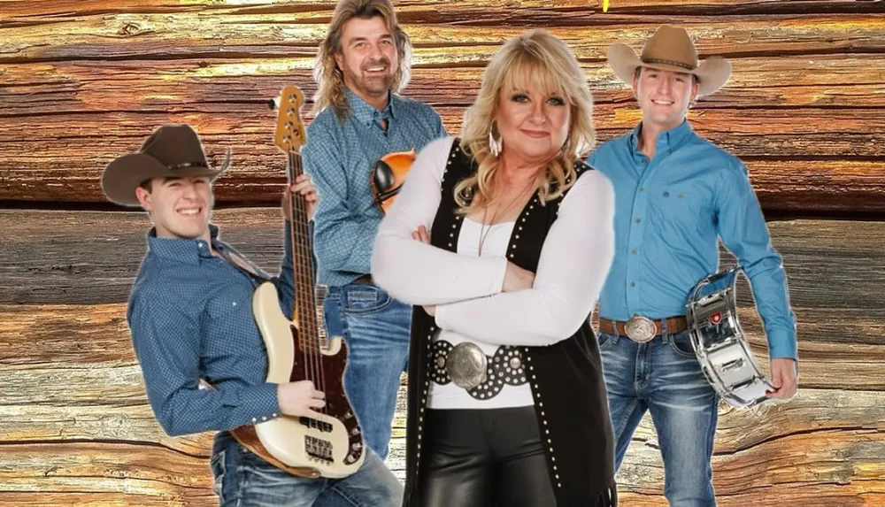 A group of four smiling people two wearing cowboy hats pose with musical instruments against a wooden backdrop