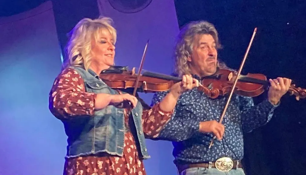 Two people are playing violins on stage