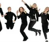 Five people dressed in black are joyfully jumping in the air against a white background