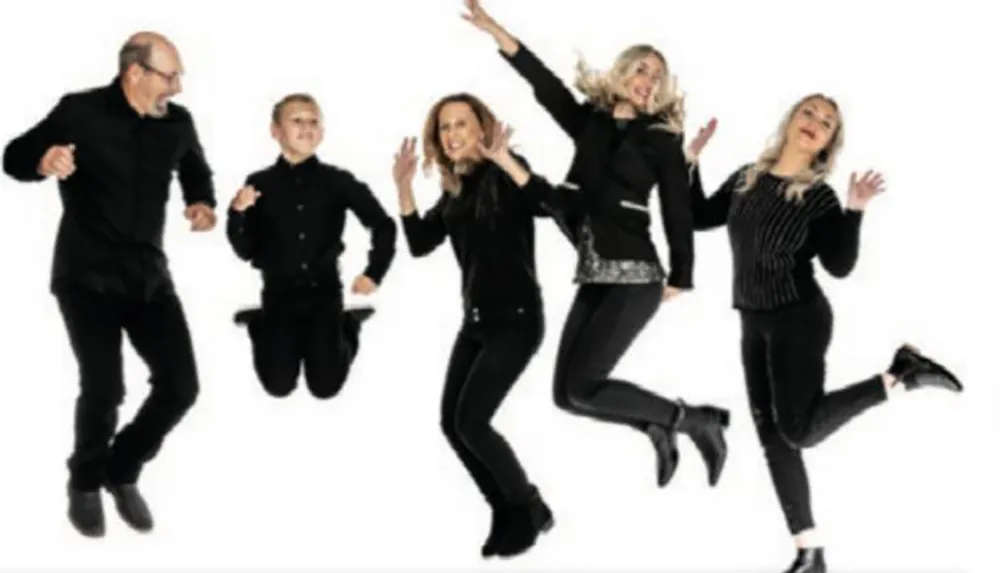 Five people dressed in black are joyfully jumping in the air against a white background
