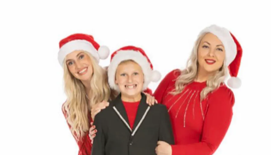 Three people, wearing Santa hats and festive red clothing, are smiling together in a holiday-themed photograph.