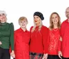 Five people are posing in festive attire with four wearing variations of red and one in a green shirt