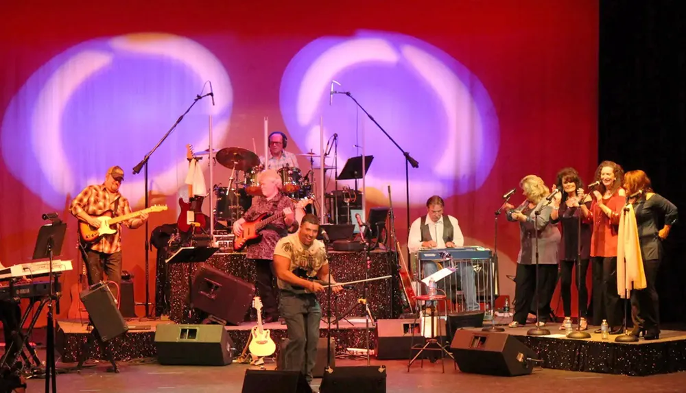 A lively band is performing on stage with bright lighting and several musicians and singers