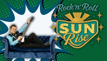 A man in a blue and black outfit is reclining on a blue sofa with a guitar, next to a vibrant 