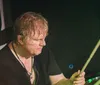 A band performs energetically on stage with a lively audience as the lead singer raises his hand in excitement