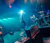 A rock band performs energetically on stage with colorful lights and instruments