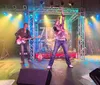A rock band performs energetically on stage with colorful lights and instruments
