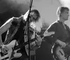 A rock band performs energetically on stage with colorful lights and instruments