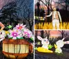 The image shows a glowing lantern sculpture of a farmer in front of a covered wagon surrounded by large illuminated flowers and barrels set against a dark wooded background