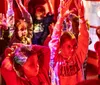 Several people are seated in red-lit chairs wearing virtual reality headsets appearing engaged and animated
