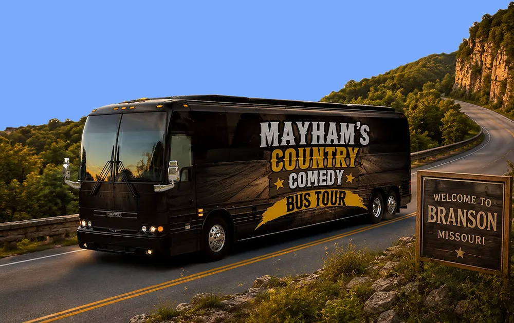 A tour bus labeled Mayhams Country Comedy Bus Tour drives along a scenic road near Branson Missouri with a Welcome to Branson sign visible