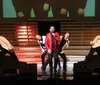 A group of performers is singing passionately on a dramatically lit stage accompanied by red lighting and stage smoke